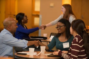 Professionals shake hands with students at UMBC at a career development workshop.